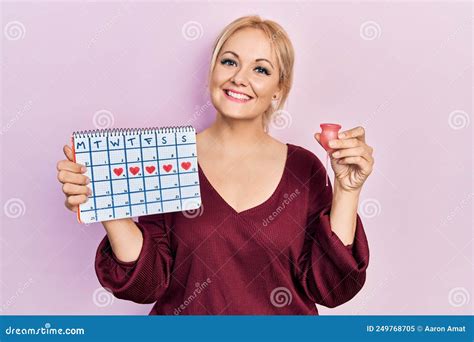Jeune Femme Blonde Tenant Le Calendrier Cardiaque Et La Coupe Menstruelle Souriant Avec Un