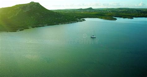 Aerial of Lone Sailboat Laying in Green Bay Surrounded by Hills during ...