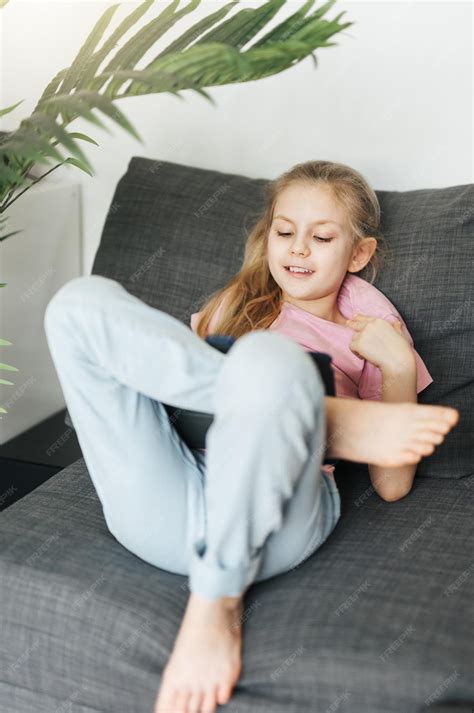 Premium Photo | Little girl lying on the couch with an electronic ...