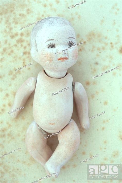 Vintage Bisque Naked Baby Doll With Large Painted Eyelashes Lying On Antique Paper Stock Photo