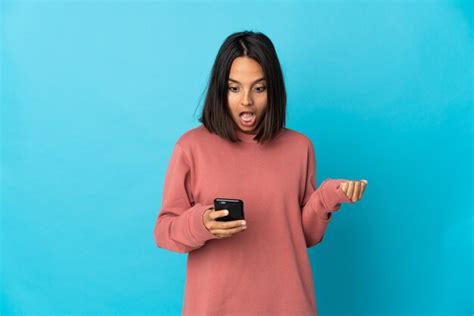 Mujer Latina Joven Aislada En La Pared Azul Sorprendida Y Enviando Un Mensaje Foto Premium