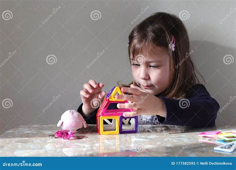 Une Petite Fille Blonde Aux Cheveux Blonds Lâches Construit Une Maison De Jouets Photo stock