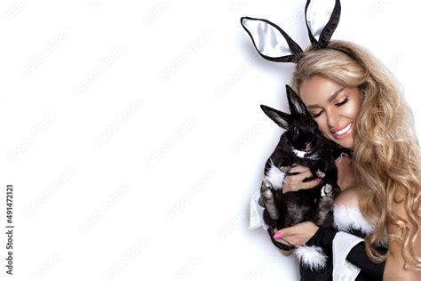 Sexy Blonde Woman Dressed In Easter Bunny Costume Is Standing On A White Background And Is
