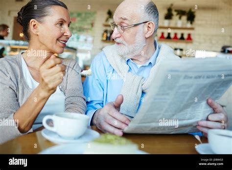 Mature Man And Woman Discussing News From Newspaper Stock Photo Alamy