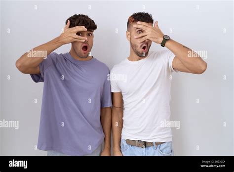 Homosexual Gay Couple Standing Over White Background Peeking In Shock Covering Face And Eyes
