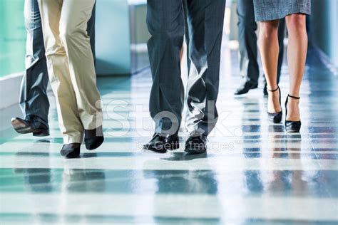 Group Of Business People Walking On Corridor In Office Building Stock