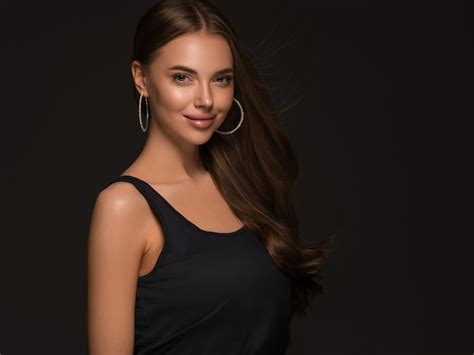 Premium Photo Beautiful Woman With Long Healthy Curly Brunette Hair Earrings Black Dress Black