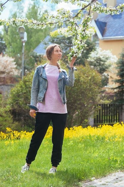 Premium Photo A Slender Beautiful Blonde Enjoys Flowering Trees And Inhales Their Fragrance