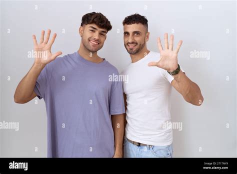 Homosexual Gay Couple Standing Over White Background Showing And Pointing Up With Fingers Number