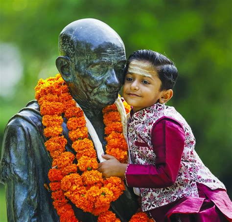 A Child Hugs A Statue Of Mahatma Gandhi After Paying Tribute On His