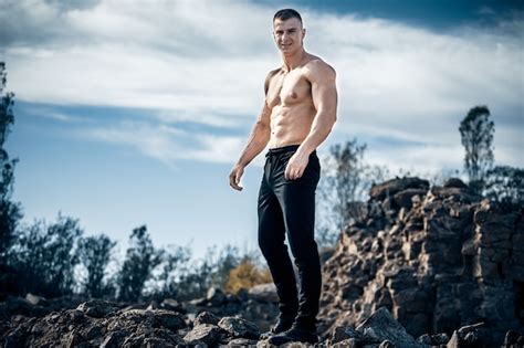 Premium Photo Strong Bodybuilder Standing On Rock With Naked Torso Sunny Day And Blue Sky
