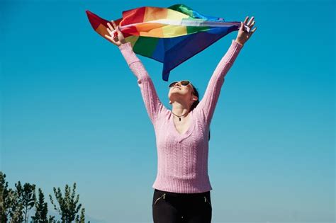 Mujer sosteniendo la bandera del arco iris gay en la cima de la montaña al aire libre Foto Premium