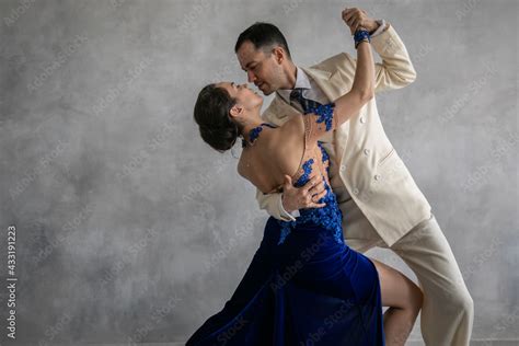 Couple Of Professional Tango Dancers In Elegant Suit And Blue Dress Pose In A Dancing Movement