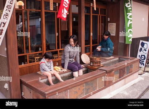 A Mother And Her Son Soak Their Feet In Hot Spring Water Outside A Shop In Shima Onsen Gunma