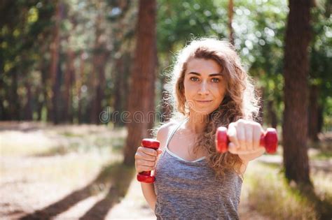 Beautiful Girl Exercising With Red Dumbbells Fitness Sport In Park