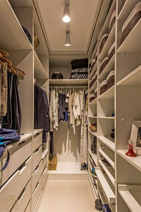 A Walk In Closet Filled With Lots Of White Shelves And Hanging Clothes