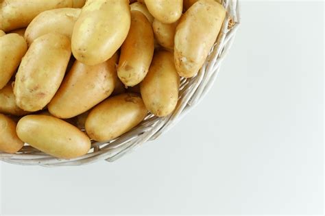 Pommes de terre dans un panier en osier sur tableau blanc mise à plat