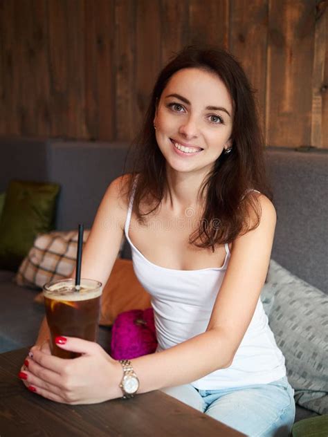 Beautiful Cute Brunette Girl Sitting In The Cozy Cafe Near The Window Enjoying Big Cup Coffee