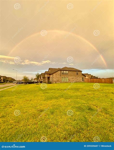 Vertical View of a Rainbow Arch Over the Houses with Grass Field Under