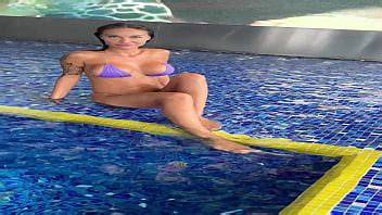 Monika Fox En Bikini Morado Nada En La Piscina Y Posa Junto A La Ventana Con La Ciudad De Fondo