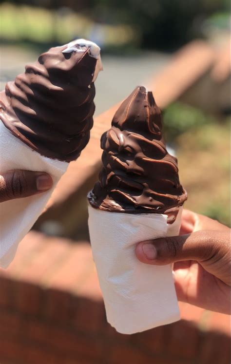 Two Ice Cream Cones With Chocolate Frosting On Top