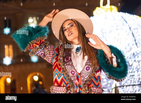 Stilvolle blonde Frau in einem Hut posiert in der geschmückten Straße in der Nacht in der