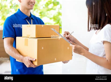 Woman Signing Document Receiving Parcel Box From Delivery Man