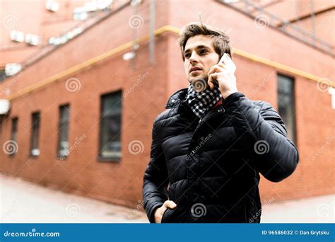 Portrait Of Confident Smiling Hot Guy Wearing Casual Clothing Walking On The Street Beside Brick