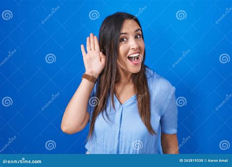 Young Brunette Woman Standing Over Blue Background Waiving Saying Hello