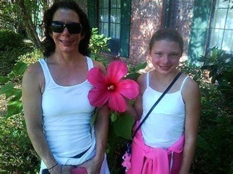 Two Women Standing Next To Each Other Holding Pink Flowers