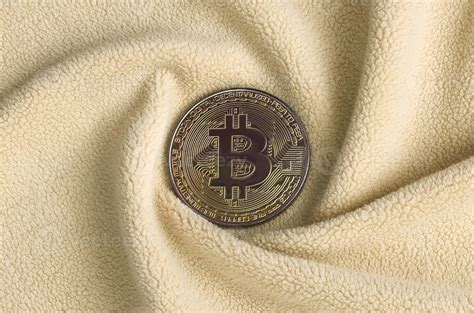The golden bitcoin lies on a blanket made of soft and fluffy light ...