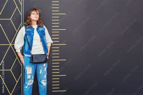 Girl stands next to a large scale ruler. Measurement of a woman in full ...