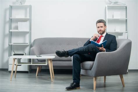 Smiling Mature Businessman In Suit Sit In Office Reading Book Stock