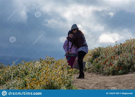 Latina Mother And Daughter In Front Of Desert California Poppy Field On Path With Orange And