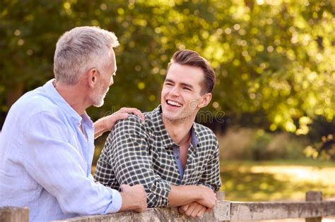 Mature Father With Adult Son Leaning On Fence Walking In Countryside Stock Photo Image Of
