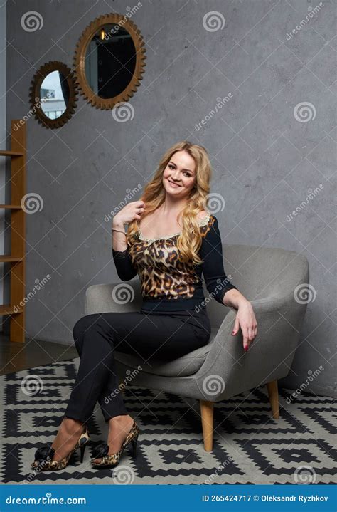 Portrait Of Beautiful Blonde Woman In Black Suit Sitting On In Classic Interior Stock Image