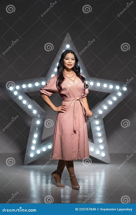 Asia Milf Model Stands Half A Turn Against The Backdrop Of A Giant Star In The Dark Studio