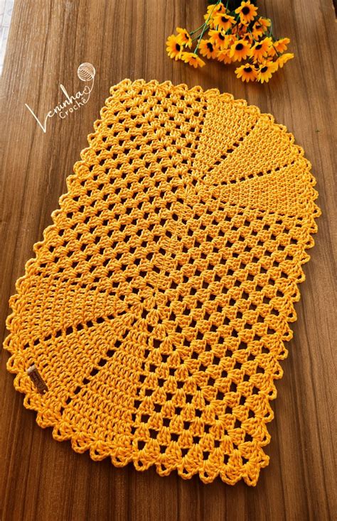 A Yellow Crocheted Doily Sitting On Top Of A Wooden Table Next To Flowers