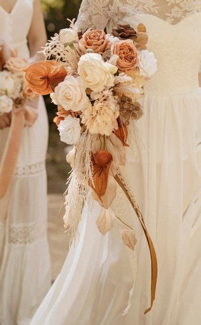 Two Bridesmaids In White Dresses Holding Bouquets With Feathers And