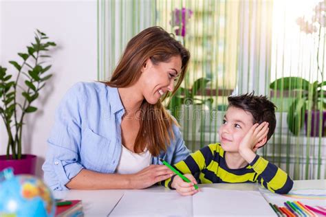 Cute Boy With Mother Doing Homework At Home A Mother Helps Her Little