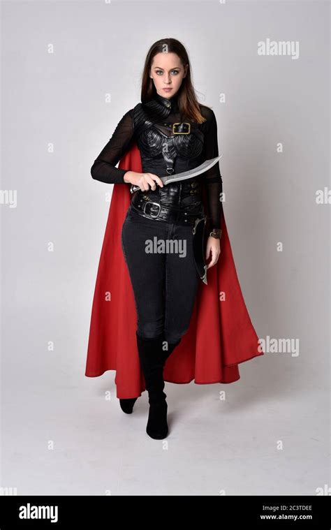Portrait Of Brunette Girl Wearing Black Leather Catsuit Red Cloak Full Length Standing Pose