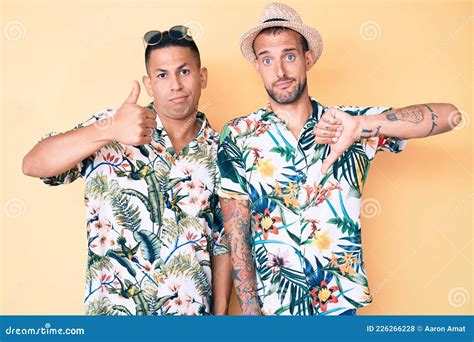 Joven Pareja Gay De Dos Hombres Con Sombrero De Verano Y Camiseta Hawaiana Haciendo El Pulgar