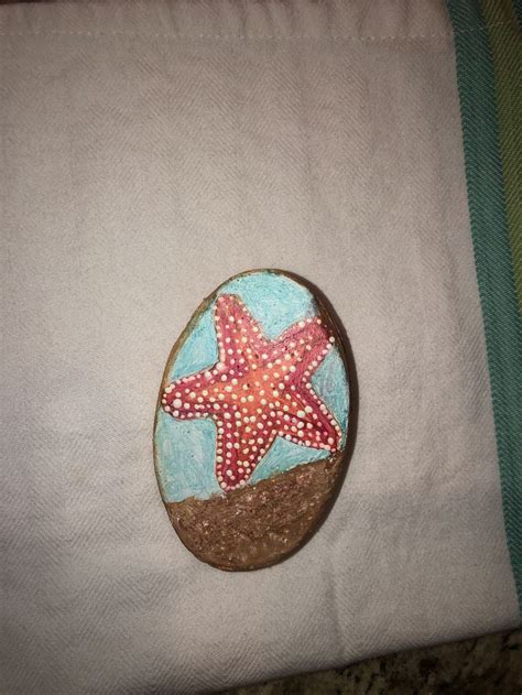 A Rock With A Starfish Painted On It Sitting On Top Of A White Cloth