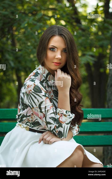 Beautiful Brunette Girl Poses And Relaxed On Bench Outdoors Stock Photo Alamy