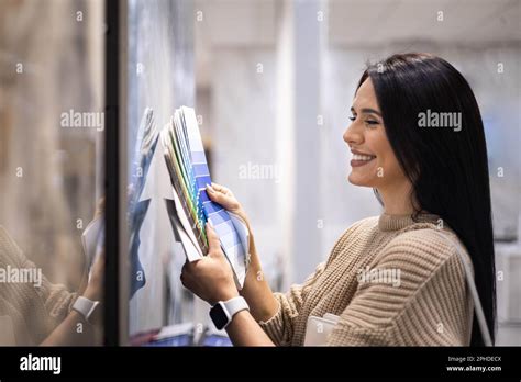 Happy Brunette Female Interior Designer Choosing Flooring Tile Color Texture Samples At Store
