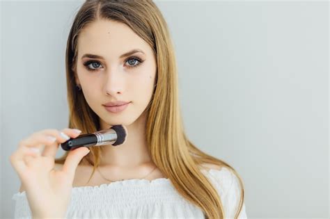 Une Belle Jeune Fille Blonde Se Maquille Devant Le Miroir Photo Gratuite