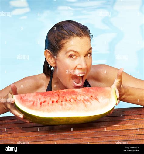 Brunette Attractive Woman Biting In Piece Of Melon In Summer Stock Photo Alamy