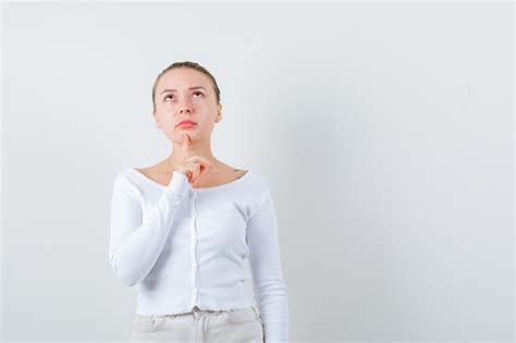 La Fille Blonde Met Son Doigt Sous Son Menton Sur Le Fond Blanc Photo Premium