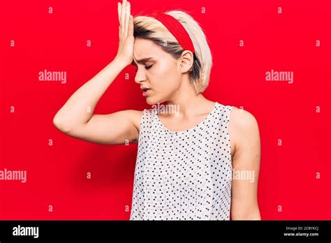 Jeune belle femme blonde portant des vêtements décontractés surpris de la main sur la tête pour