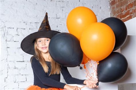 Une Petite Fille Blonde Souriante Dans Un Costume De Sorci Re Tenant Des Ballons Orange Et Noirs